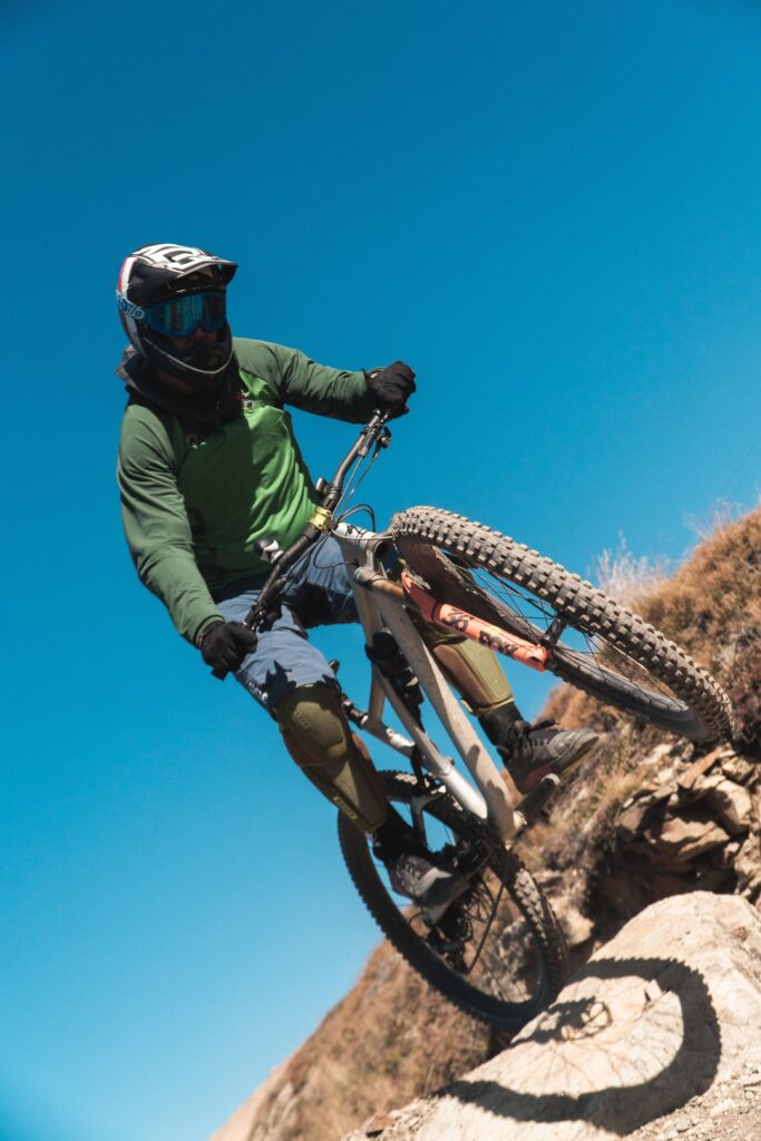 Mountain biker riding downhill on a rugged trail under a clear blue sky near Jackson Hole
