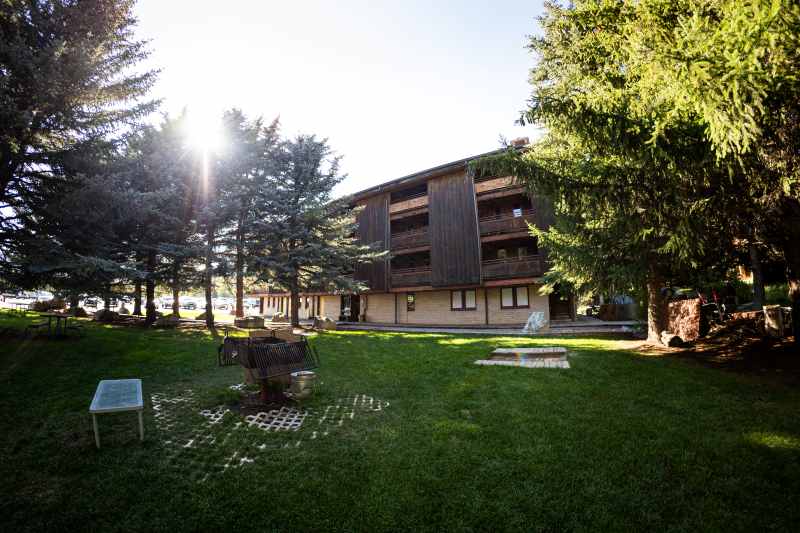 The Hostel exterior with a spacious lawn, picnic tables, and a BBQ pit